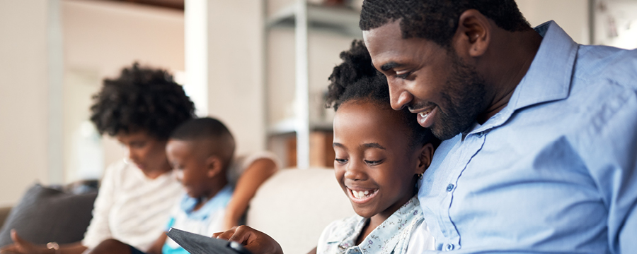 Happy family sitting on couch looking at tablets