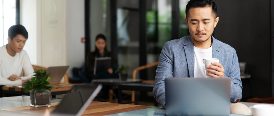 A person in a suit sitting at a table with a computer